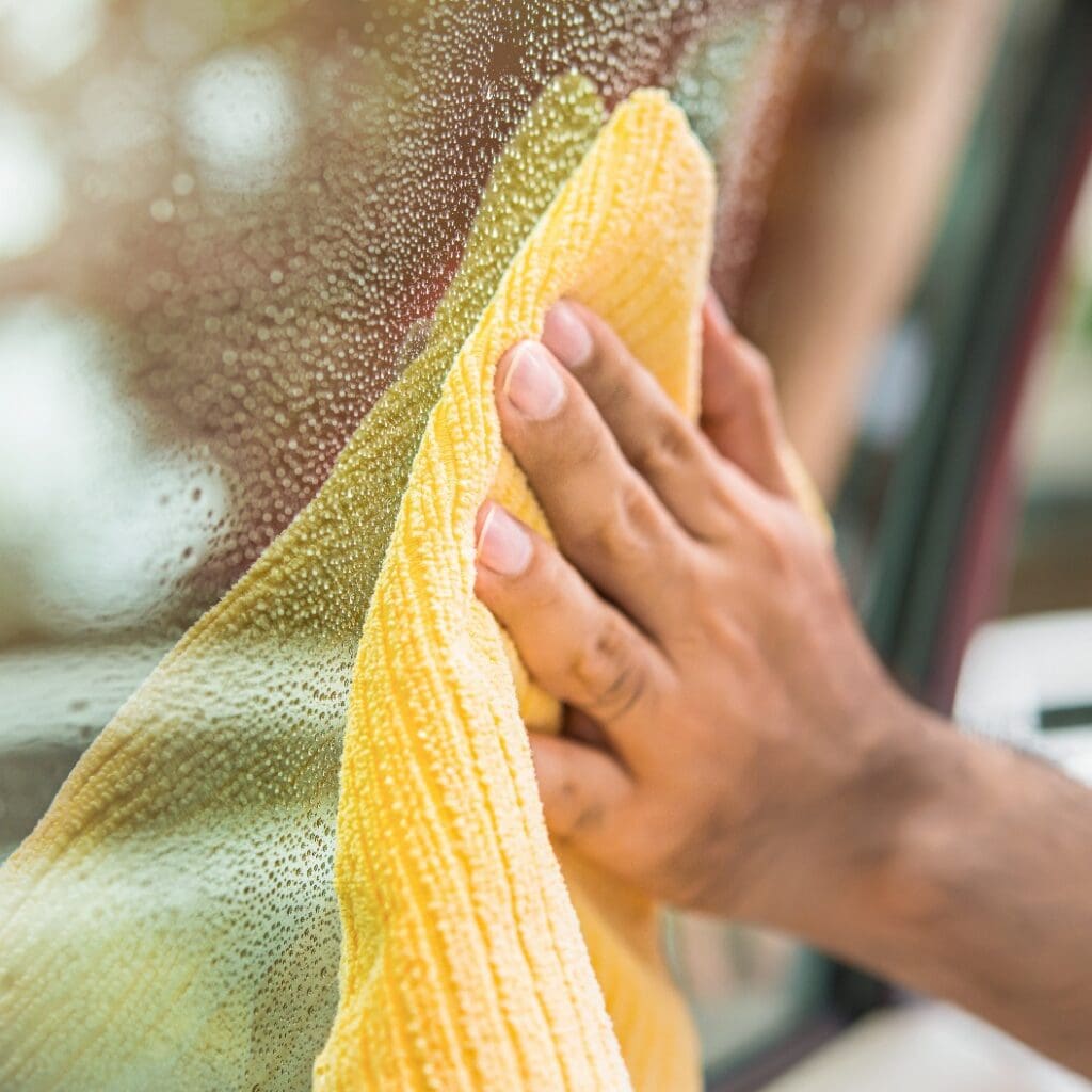 Auto care service staff cleanining car window glass